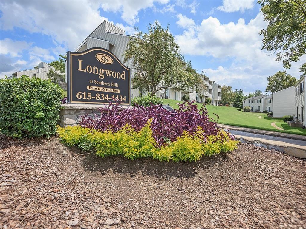 the sign for longwood apartments is in front of a yard with flowers