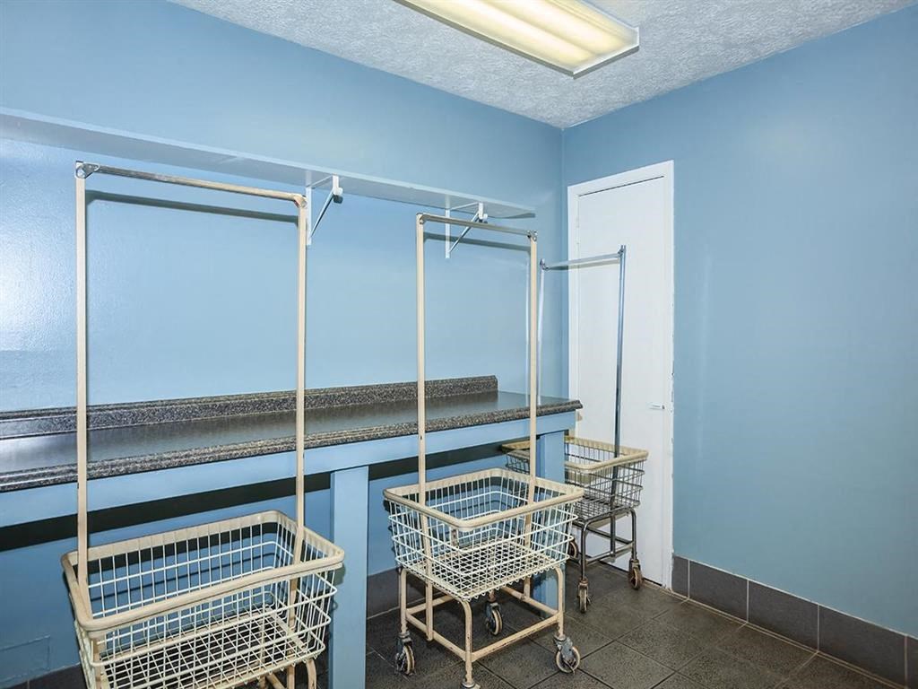 a laundry room with three baskets and a shelf