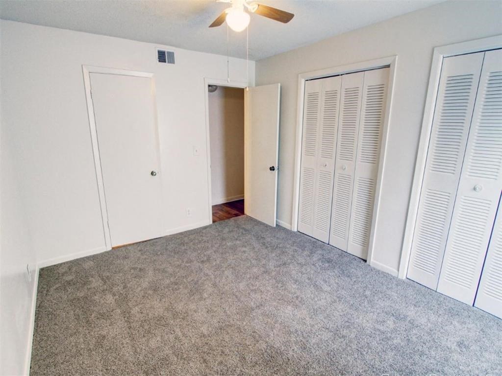 an empty living room with a ceiling fan and a closet
