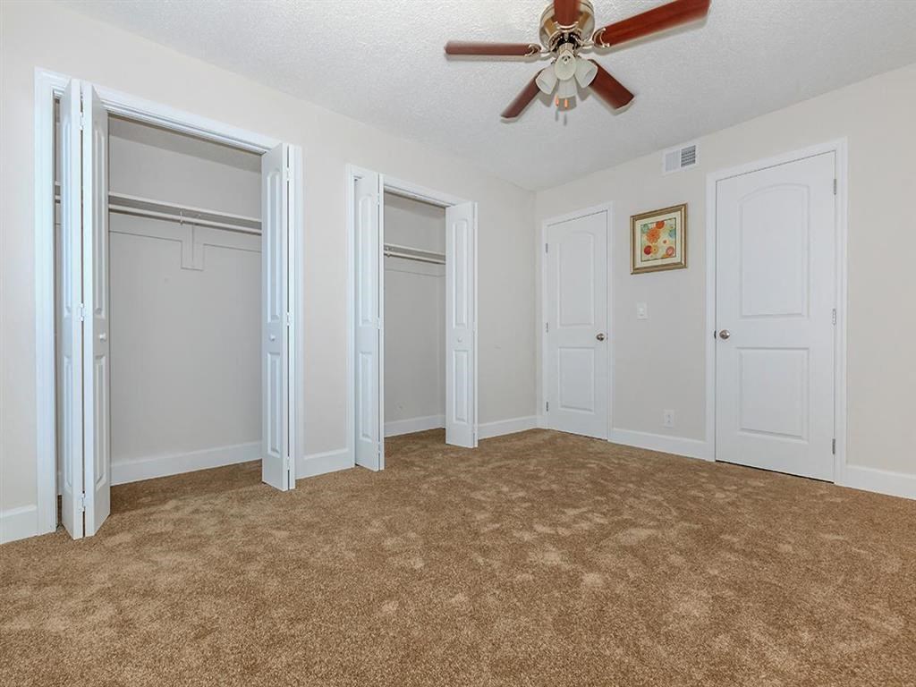 an empty living room with white doors and a ceiling fan