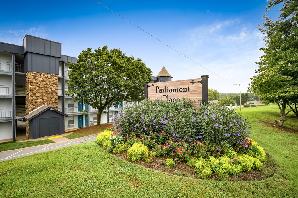 a sign for the placement place apartments in front of a flower garden
