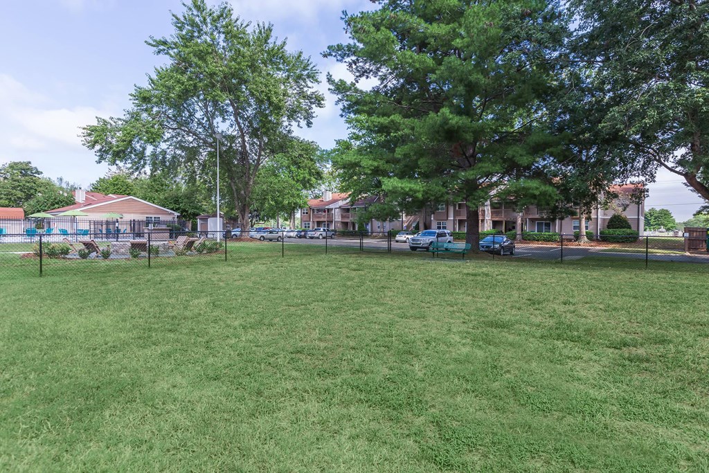 a park with grass and trees in front of a building