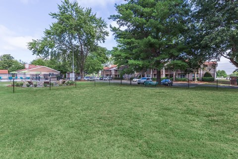 a park with grass and trees in front of a building