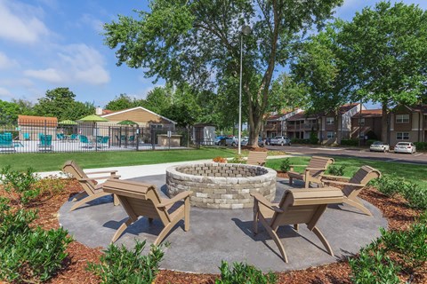 a patio with a fire pit and chairs in front of a pool