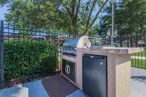 a barbecue grill in a backyard with a trash can