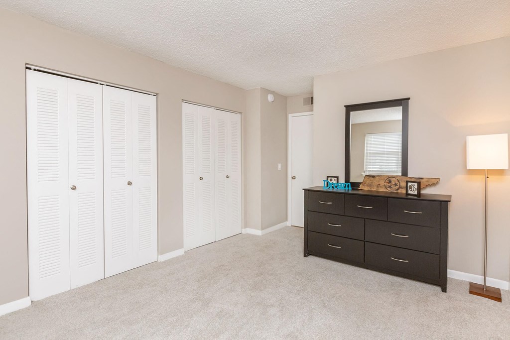 a bedroom with a dresser and closet and a mirror