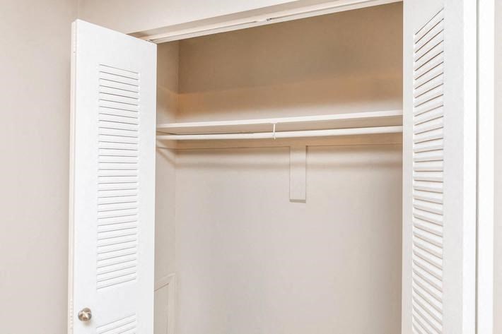 an empty closet with white shutters and a white door