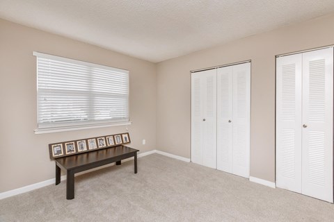 a living room with a bench and a window and two closets