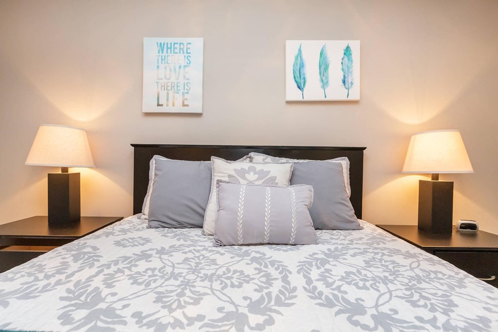 a bedroom with a bed and two lamps and pictures on the wall