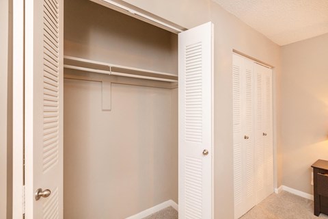 a closet with white shuttered closet doors in a bedroom