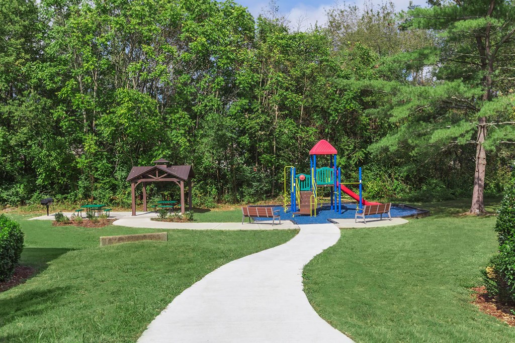 a walkway leading to a playground with a swing set