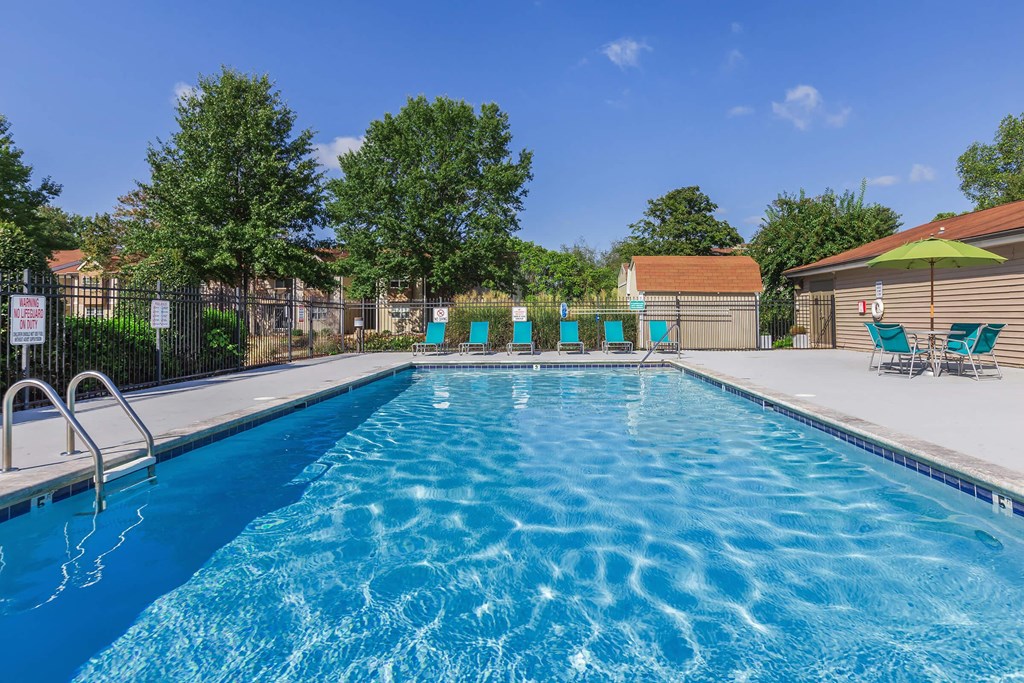 a swimming pool with chairs and umbrellas next to a resort style pool