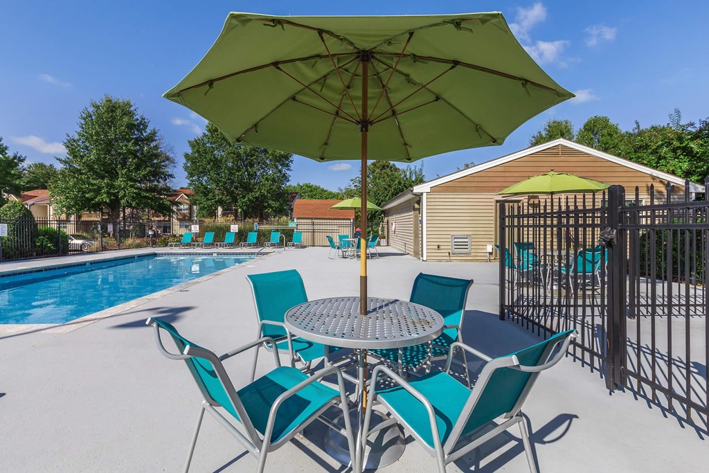 our apartments have a pool and a patio with chairs and an umbrella