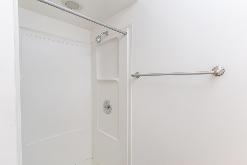 a white bathroom with a white shower and a white door