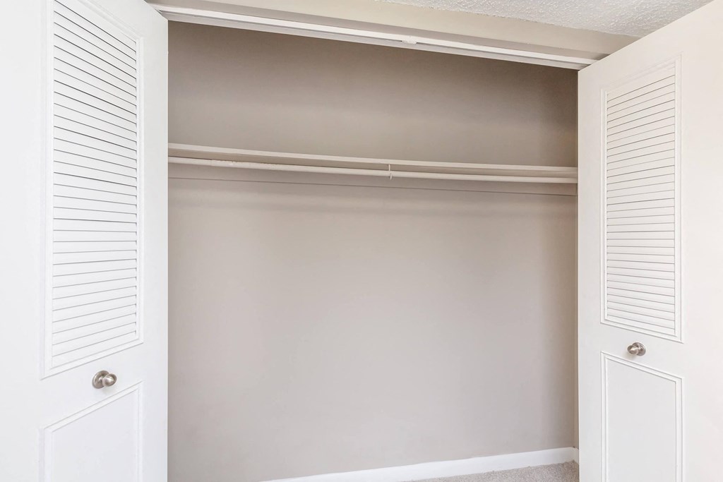 a walk in closet with white closet doors and a white door with a white closet