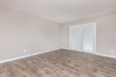 an empty living room with wood flooring and a sliding glass door
