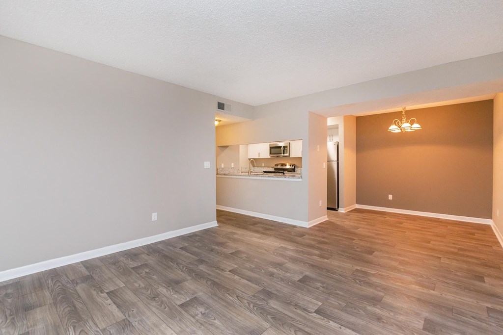 the living room and kitchen of an empty apartment with wood flooring