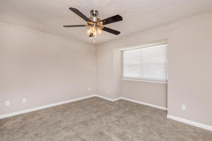 an empty room with a ceiling fan and a window