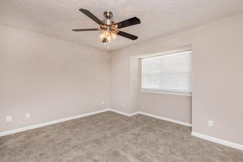 an empty room with a ceiling fan and a window