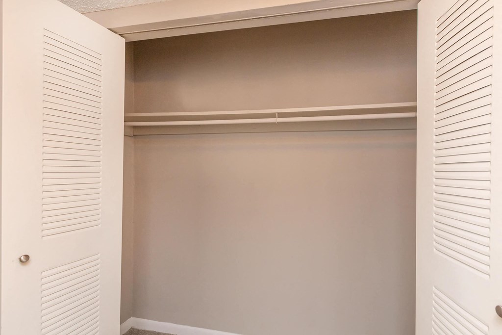 a walk in closet with white shuttered closet doors