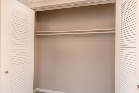a walk in closet with white shuttered closet doors