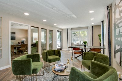 a living room with green chairs and a dining room table