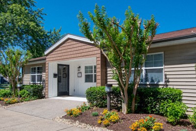 a house with a sidewalk and a tree in front of it