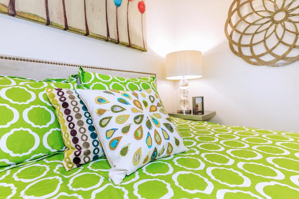 a bed with green and white sheets and pillows