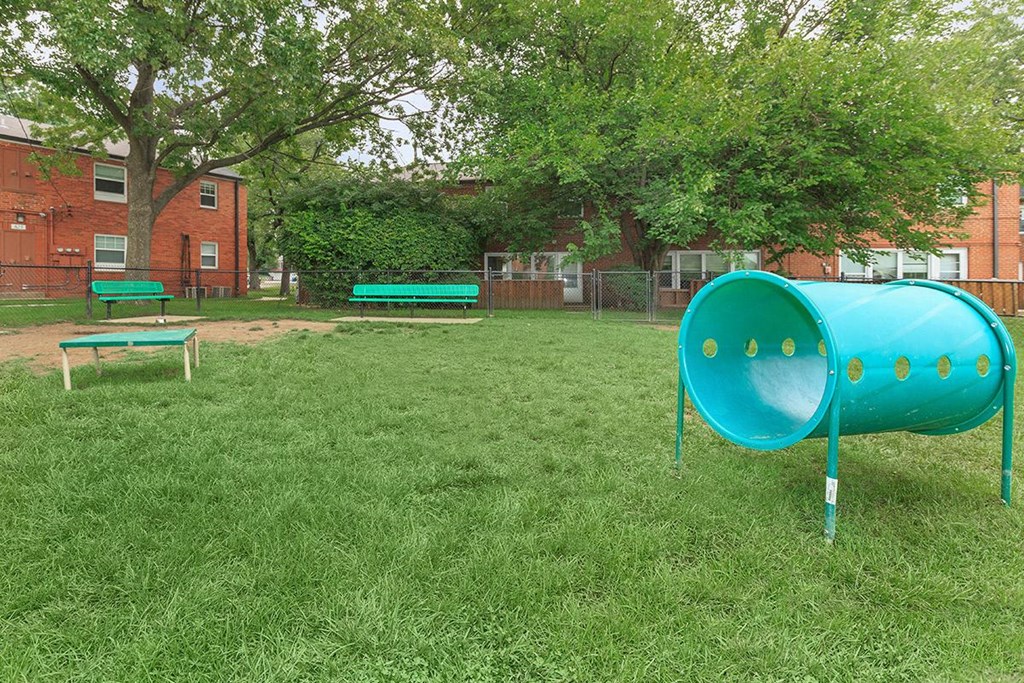 a large green park with a blue container in the grass