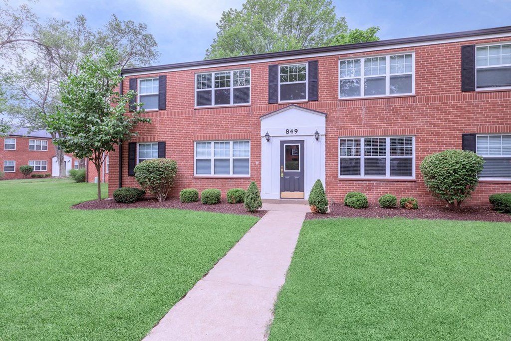 a brick house with a sidewalk in front of it