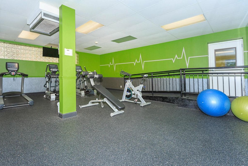 a gym with weights and a ball on the floor and green walls