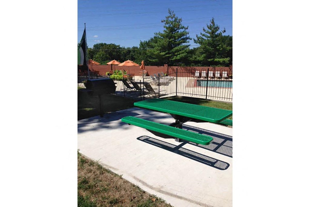 a green picnic table in front of a swimming pool
