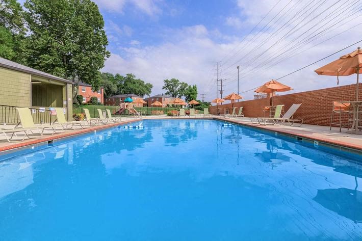 a large blue swimming pool with chairs and umbrellas