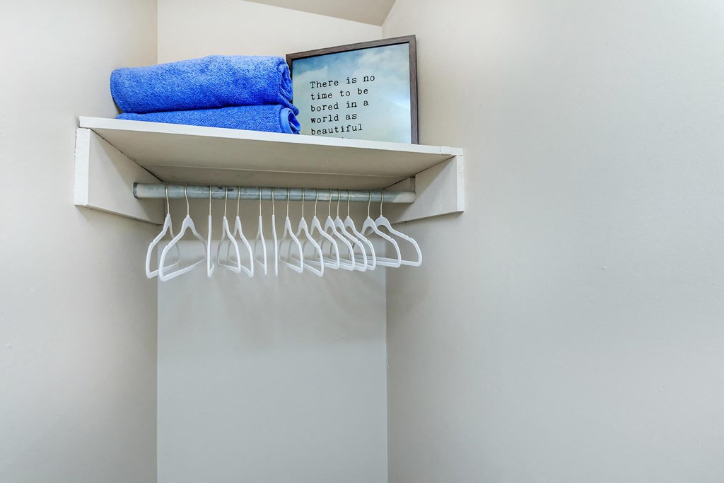 a shelf with clothes hangers and a mirror above a closet