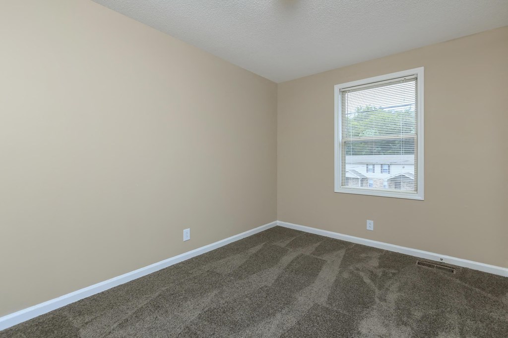 an empty room with carpet and a window
