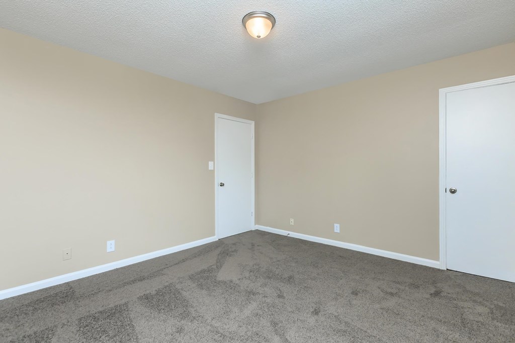 an empty living room with carpet and a door to a closet
