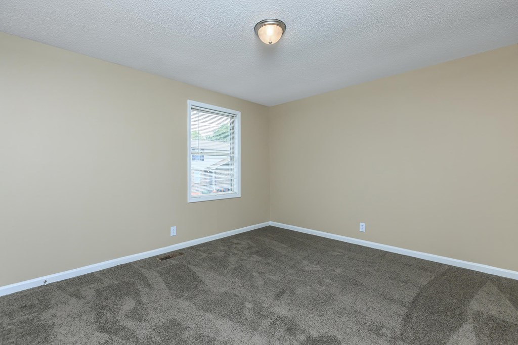 an empty living room with carpet and a window