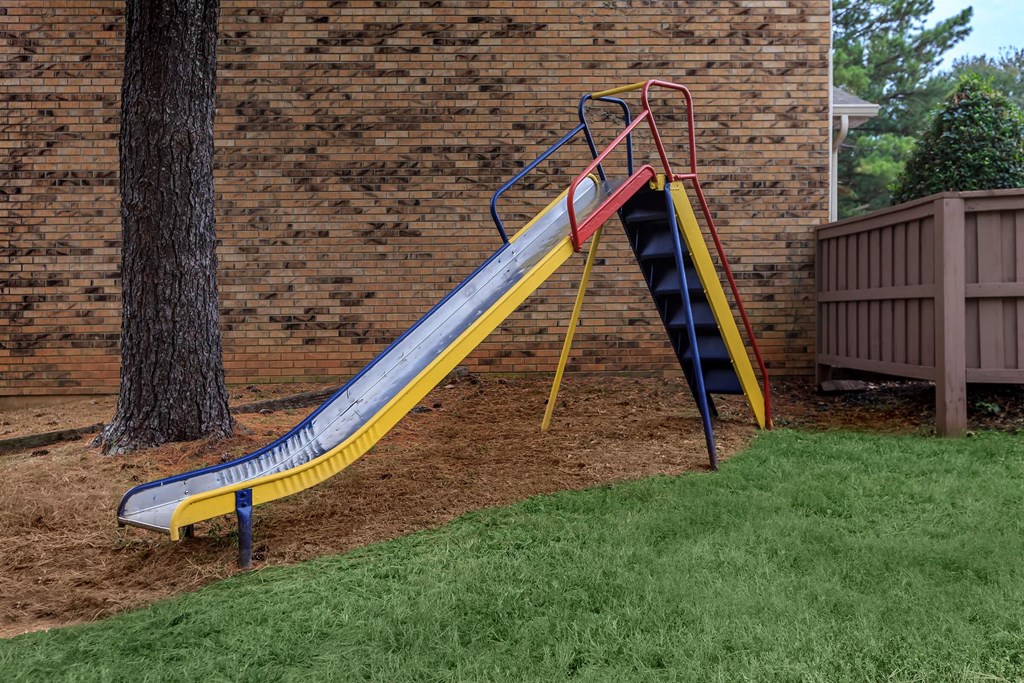 a slide in a backyard next to a tree