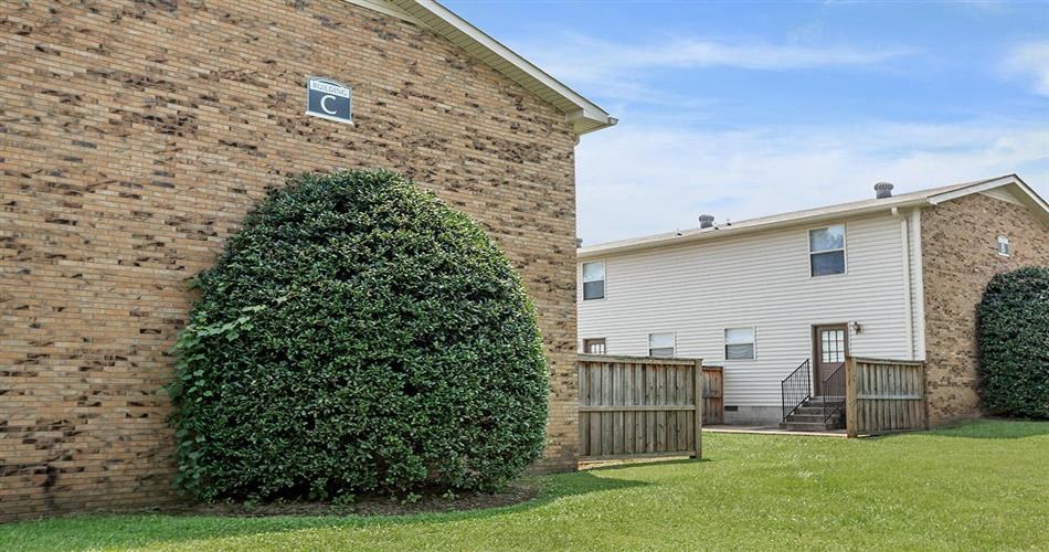 a brick building with a hedge next to a house