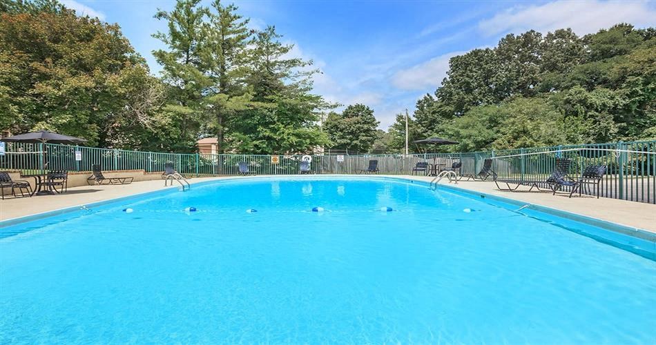 a large blue pool with chairs and a fence around it