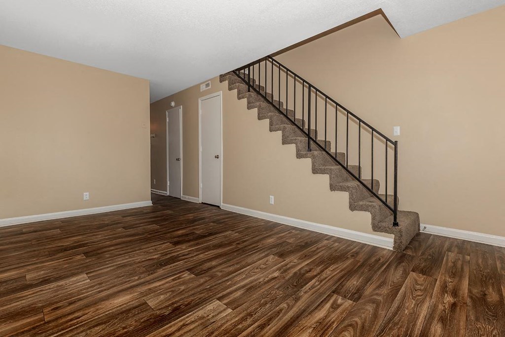 a living room with a staircase and wooden floors