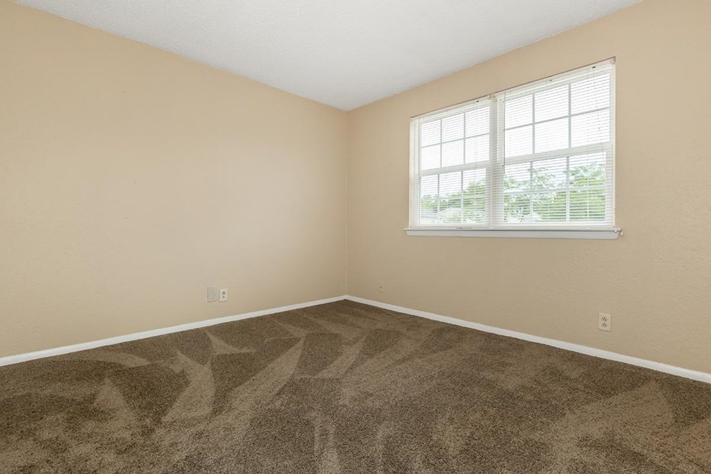 an empty room with carpet and a window