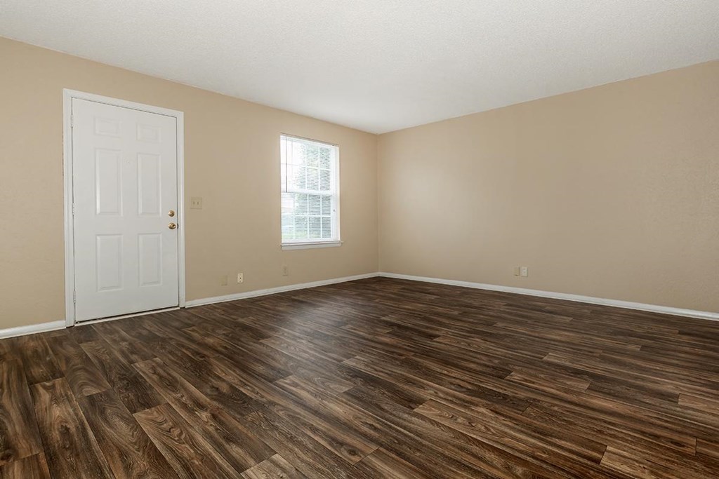 an empty living room with wood flooring and a white door