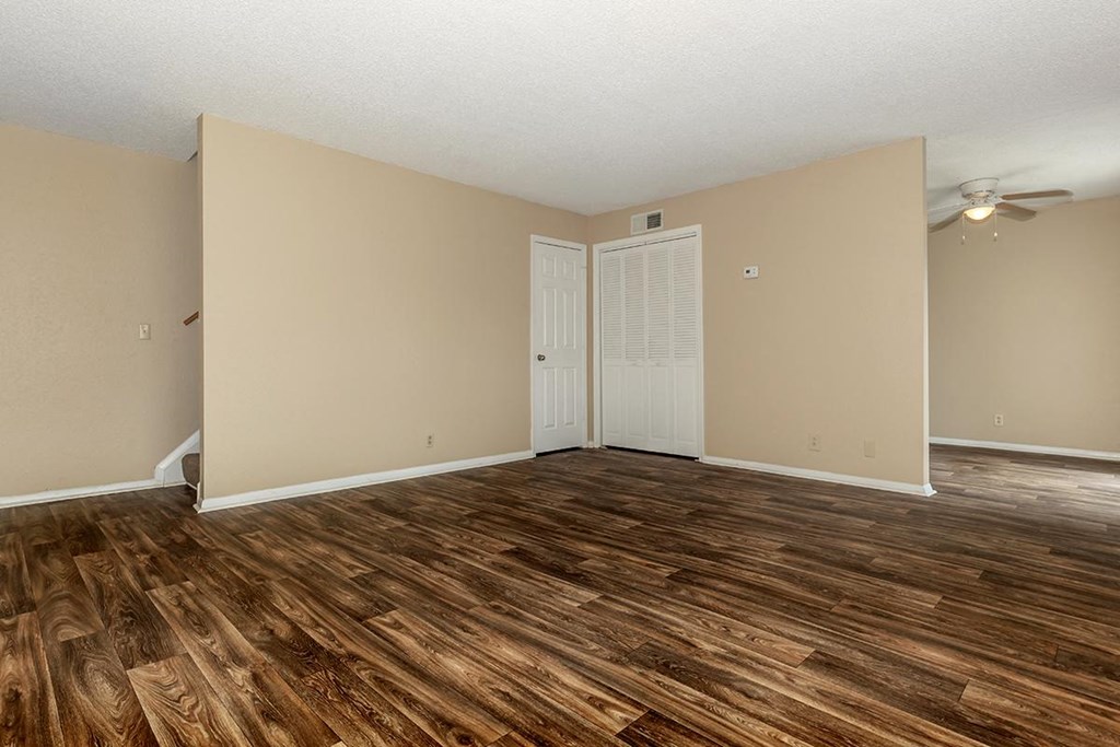 an empty living room with a hard wood floor and a closet