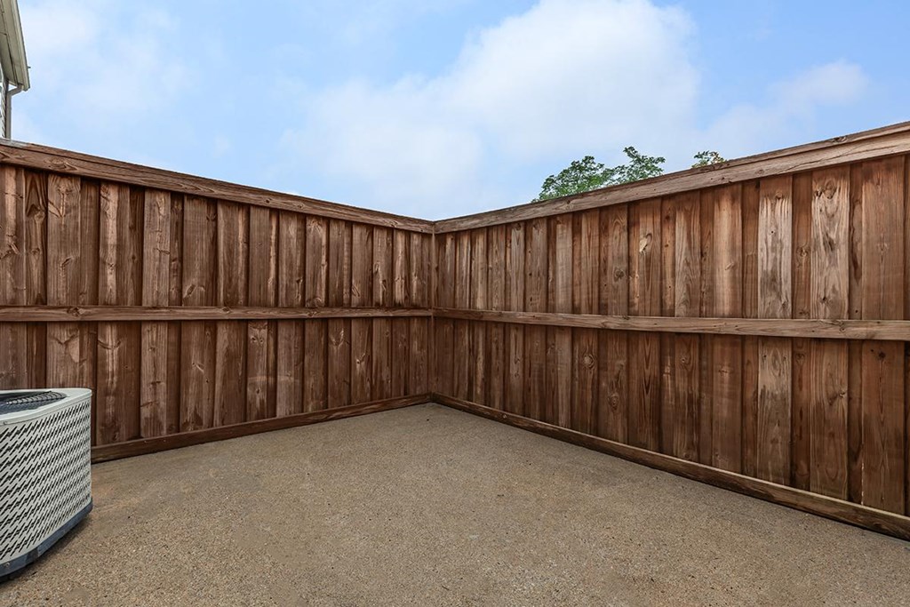 a backyard with a wooden fence and a gravel patio