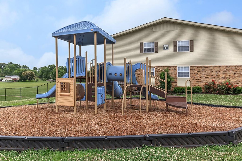 a playground with a swing set in front of a house