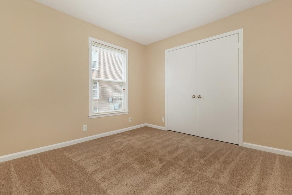 an empty bedroom with a closet and a window