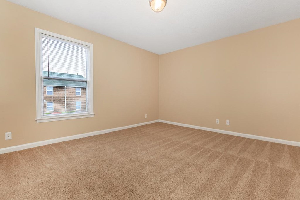 an empty living room with a window and carpet