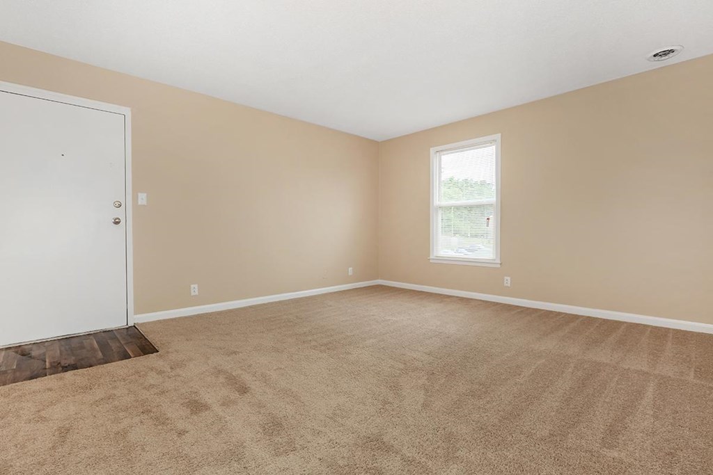 an empty living room with a door and carpet