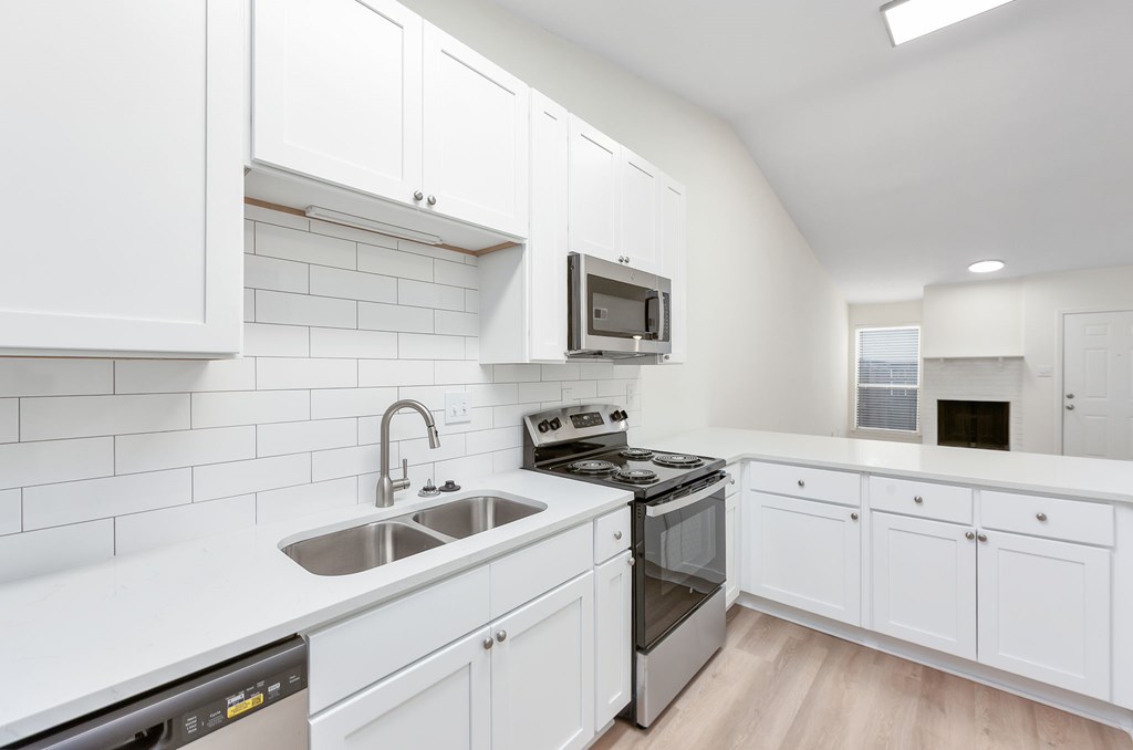 A modern kitchen with white cabinets and stainless steel appliances.